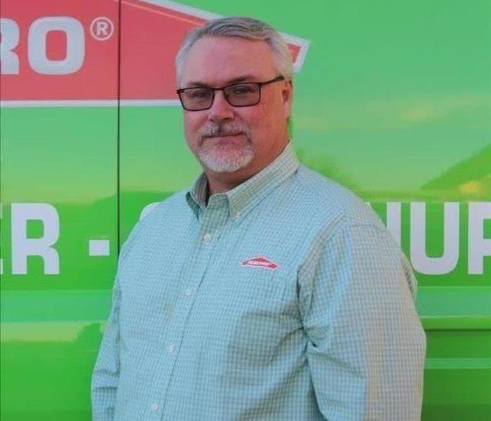 Male employee smiling standing in front of a green background