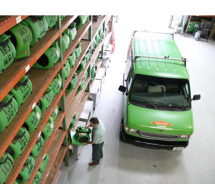 a green SERVPRO van parked in a warehouse full of equipment
